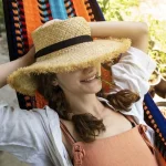 Woman lying on an Hammock with a straw hat made with natural fibers
