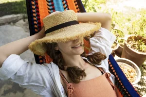 Woman lying on an Hammock with a straw hat made with natural fibers