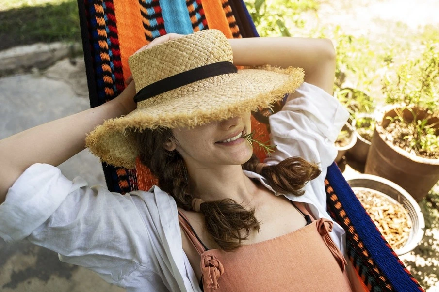 Woman lying on an Hammock with a straw hat made with natural fibers